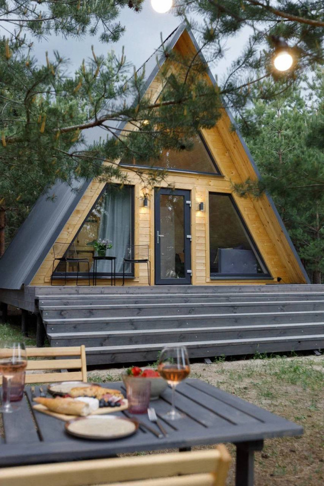 Стильный дизайн: двухэтажный, деревянный мини дом в скандинавском стиле с двускатной крышей, металлической крышей, серой крышей и отделкой планкеном - последний тренд