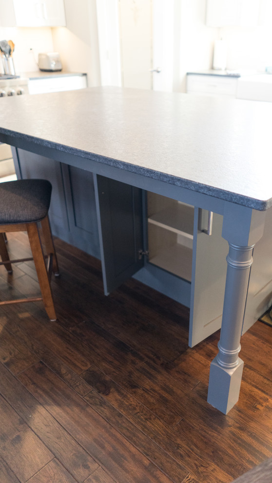 Eat-in kitchen - large transitional u-shaped eat-in kitchen idea with a farmhouse sink, flat-panel cabinets, white cabinets, granite countertops, white backsplash, ceramic backsplash, stainless steel appliances and an island