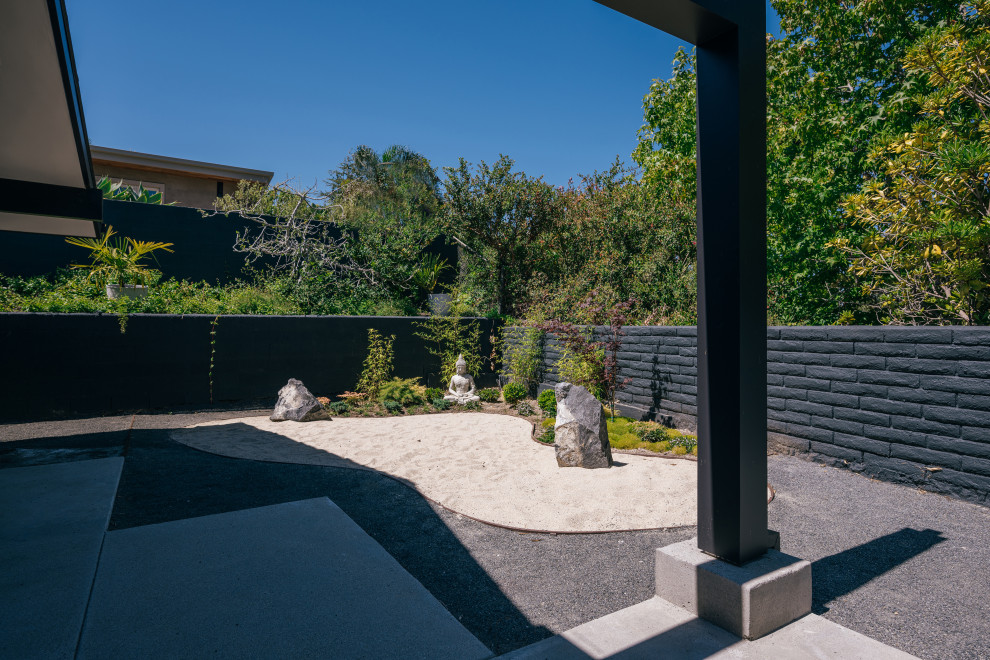 Photo of a small asian backyard full sun xeriscape in Orange County with with rock feature, decomposed granite and a stone fence.