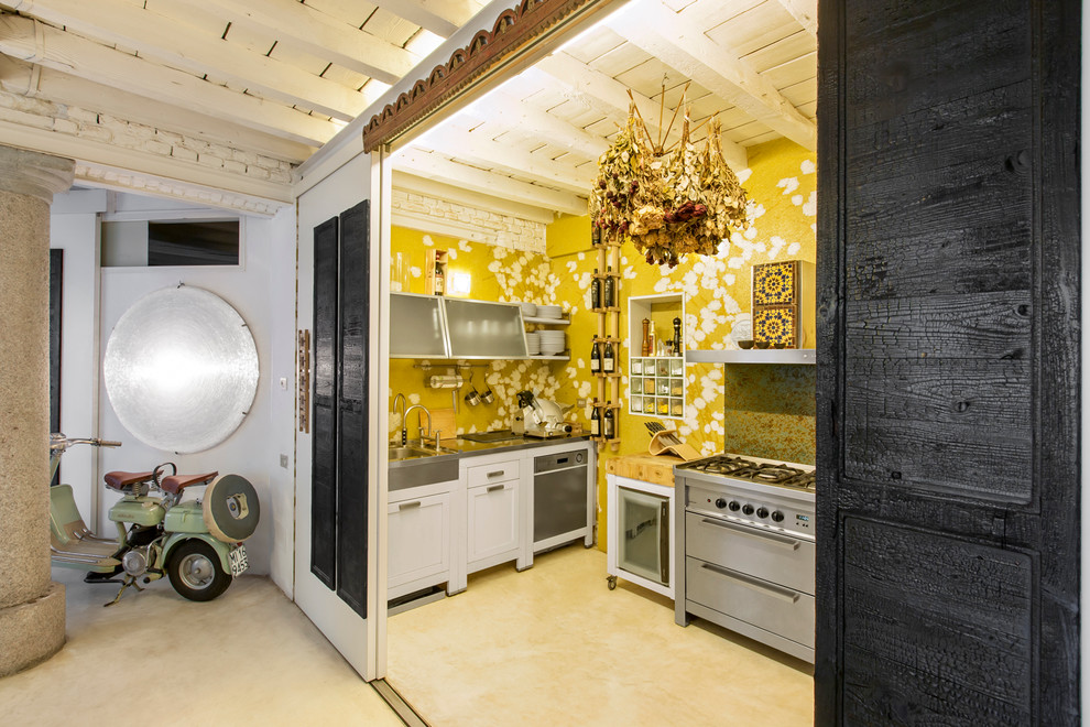 Photo of a small eclectic u-shaped separate kitchen in Milan with a drop-in sink, raised-panel cabinets, white cabinets, stainless steel benchtops, stainless steel appliances and porcelain floors.
