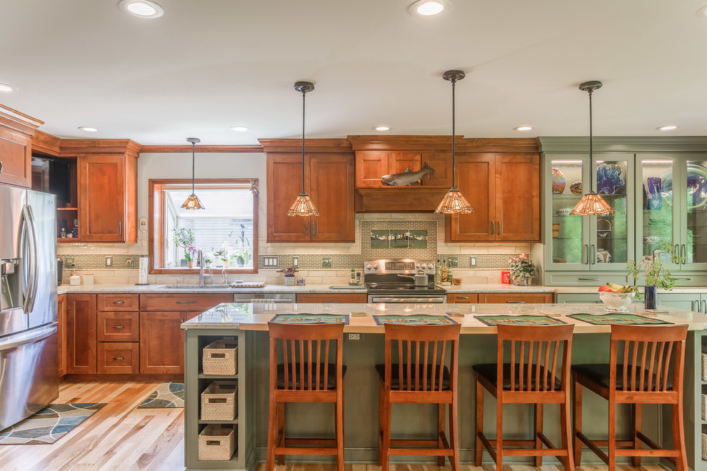 Photo of a large arts and crafts l-shaped eat-in kitchen in Detroit with an undermount sink, flat-panel cabinets, brown cabinets, granite benchtops, beige splashback, limestone splashback, stainless steel appliances, light hardwood floors, with island, brown floor and beige benchtop.