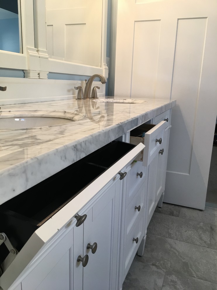 Photo of a mid-sized transitional master bathroom in DC Metro with furniture-like cabinets, white cabinets, a corner shower, gray tile, porcelain tile, blue walls, porcelain floors, an undermount sink, quartzite benchtops, grey floor and a hinged shower door.