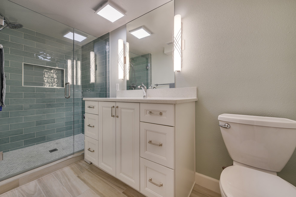 Photo of a mid-sized transitional kids bathroom in Portland with raised-panel cabinets, white cabinets, an alcove shower, a two-piece toilet, blue tile, subway tile, blue walls, porcelain floors, an undermount sink, engineered quartz benchtops, brown floor, a hinged shower door and white benchtops.