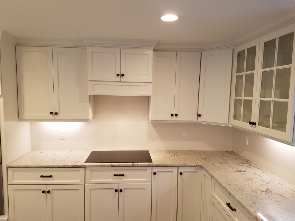Example of a mid-sized transitional l-shaped dark wood floor and brown floor eat-in kitchen design with a farmhouse sink, shaker cabinets, white cabinets, granite countertops, white backsplash, subway tile backsplash, stainless steel appliances and an island
