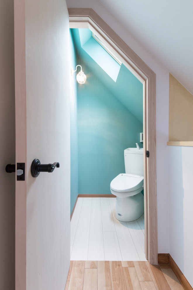 Inspiration för exotiska toaletter, med en toalettstol med hel cisternkåpa, blå väggar och vitt golv