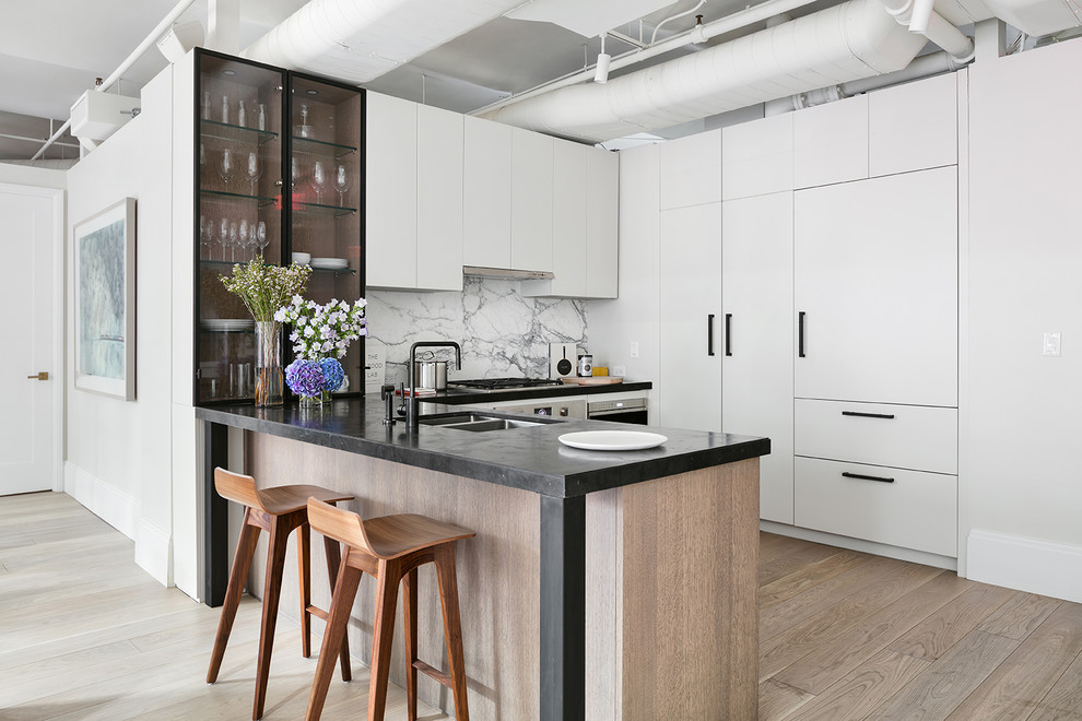 Inspiration for a mid-sized contemporary l-shaped open plan kitchen in New York with an undermount sink, flat-panel cabinets, white cabinets, white splashback, light hardwood floors and a peninsula.