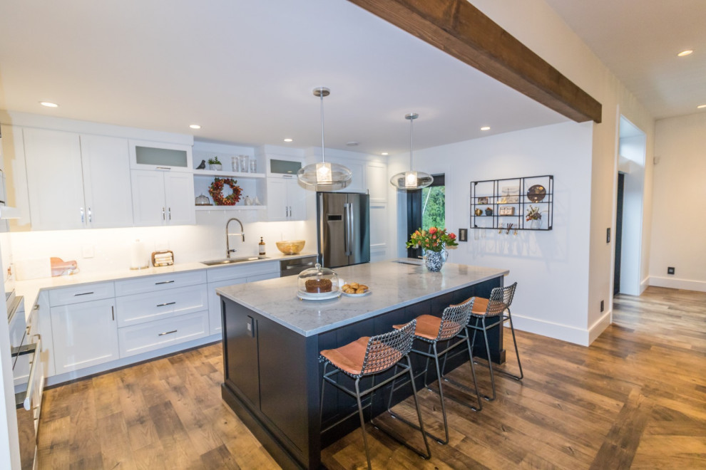 Mid-sized l-shaped dark wood floor and brown floor kitchen photo with a drop-in sink, recessed-panel cabinets, white cabinets, quartzite countertops, stainless steel appliances, an island and yellow countertops