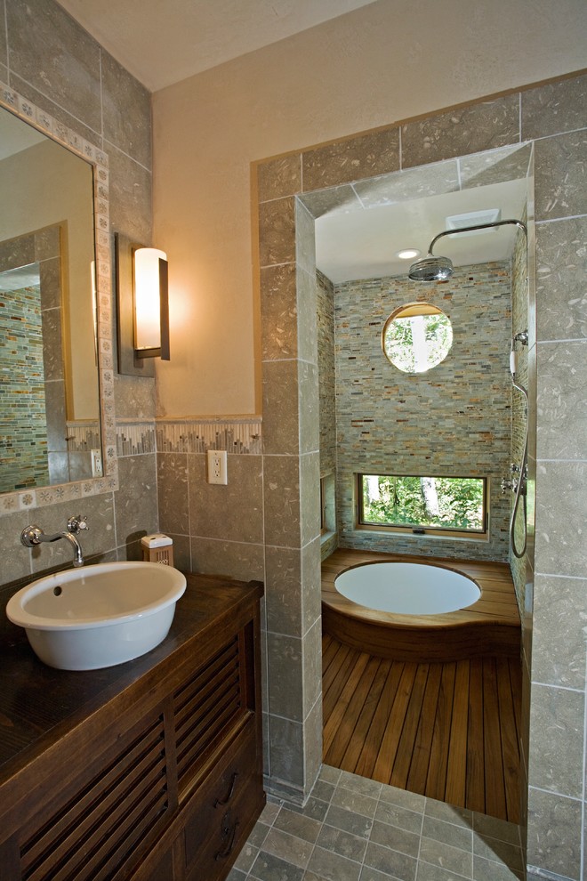 Small country master bathroom in Denver with a vessel sink, flat-panel cabinets, medium wood cabinets, wood benchtops, a japanese tub, a curbless shower, a one-piece toilet, stone tile, green walls, limestone floors and gray tile.