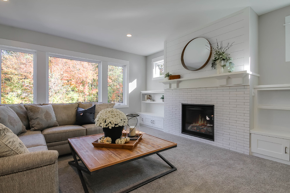 Design ideas for a mid-sized country open concept family room in Grand Rapids with grey walls, carpet, a standard fireplace, a brick fireplace surround, a freestanding tv and grey floor.
