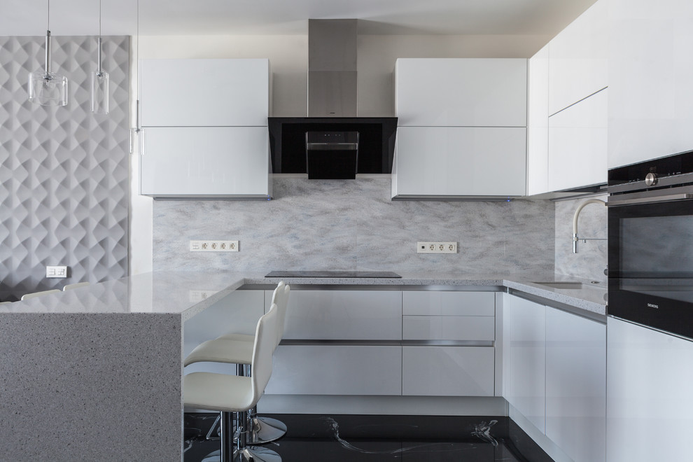 This is an example of a mid-sized contemporary u-shaped open plan kitchen in Moscow with an undermount sink, flat-panel cabinets, white cabinets, solid surface benchtops, grey splashback, marble splashback, black appliances, vinyl floors, black floor and grey benchtop.