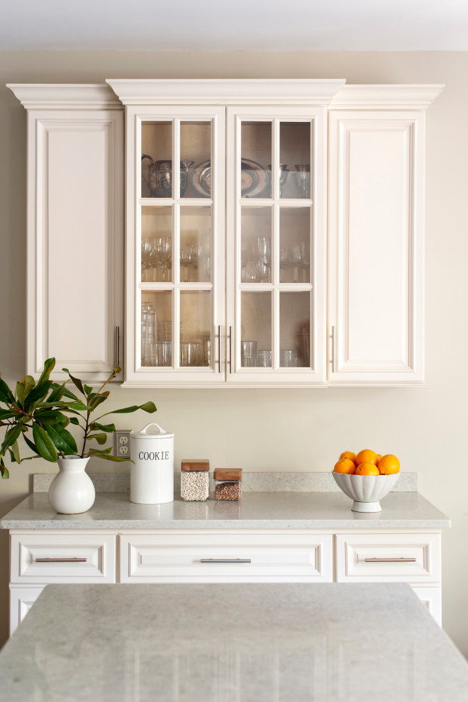 Mid-sized transitional galley medium tone wood floor and brown floor enclosed kitchen photo in Raleigh with a drop-in sink, raised-panel cabinets, beige cabinets, quartz countertops, beige backsplash, mosaic tile backsplash, stainless steel appliances, an island and beige countertops