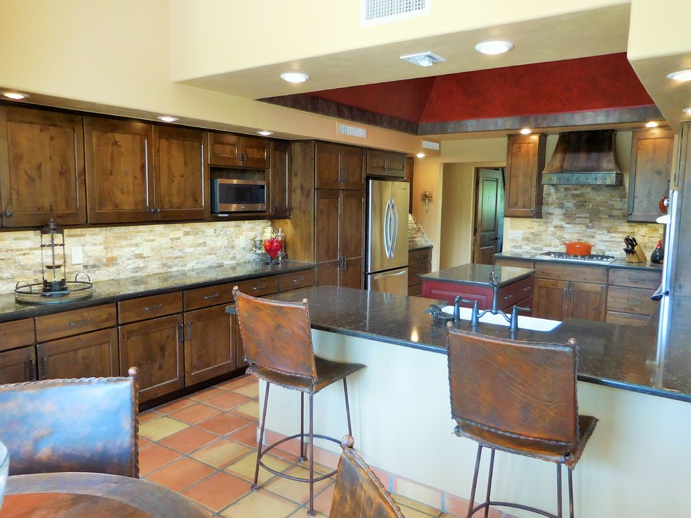 This is an example of a small separate kitchen in Phoenix with a farmhouse sink, shaker cabinets, brown cabinets, quartz benchtops, beige splashback, stone tile splashback, stainless steel appliances, terra-cotta floors and with island.