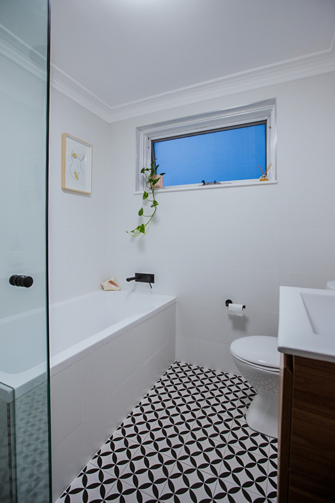 Inspiration for a small contemporary bathroom in Sydney with a corner tub, white tile, ceramic tile, white walls and ceramic floors.