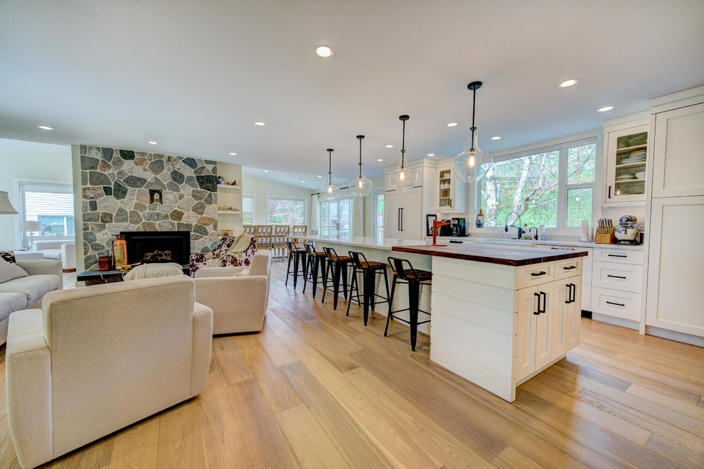 Inspiration for a mid-sized transitional l-shaped medium tone wood floor and beige floor eat-in kitchen remodel in Vancouver with an undermount sink, shaker cabinets, white cabinets, quartz countertops, white backsplash, ceramic backsplash, stainless steel appliances and an island