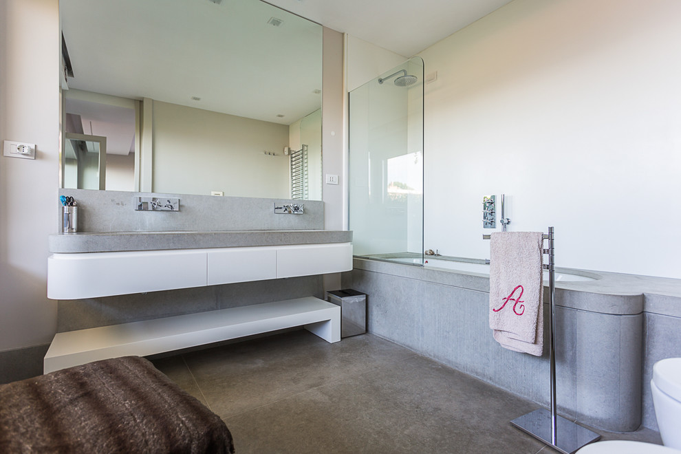 Design ideas for a mid-sized contemporary master bathroom in Naples with flat-panel cabinets, white cabinets, a corner tub, a shower/bathtub combo, white walls, concrete floors, an undermount sink, concrete benchtops and an open shower.