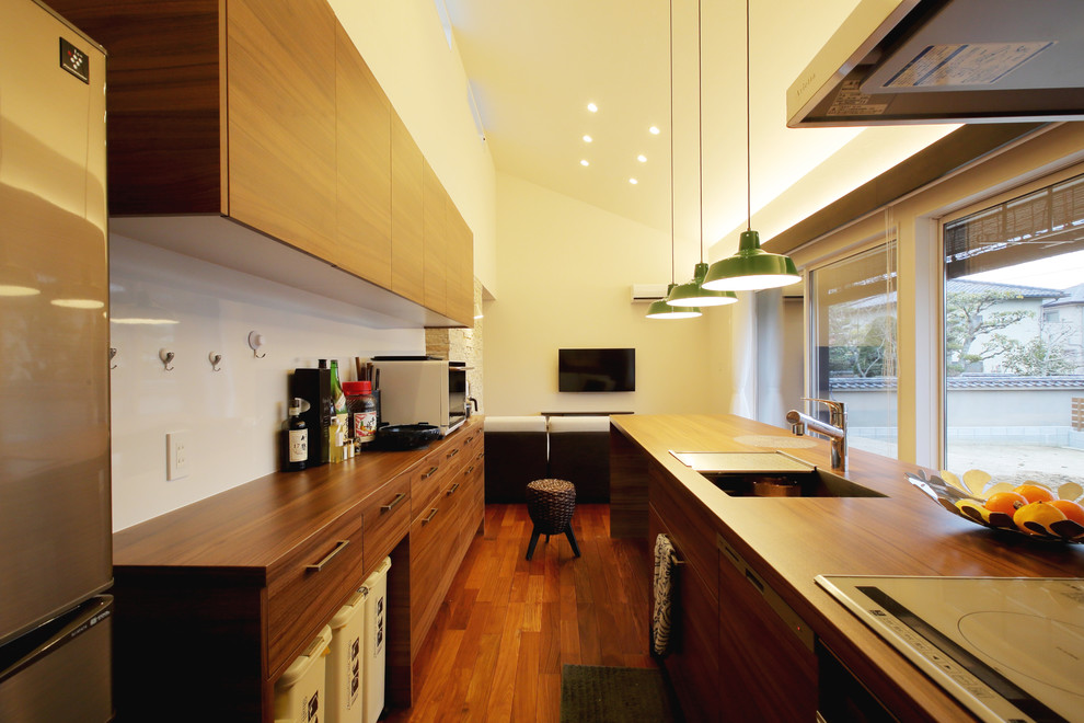This is an example of an asian galley open plan kitchen in Tokyo with a single-bowl sink, flat-panel cabinets, medium wood cabinets, wood benchtops, medium hardwood floors, with island and brown floor.