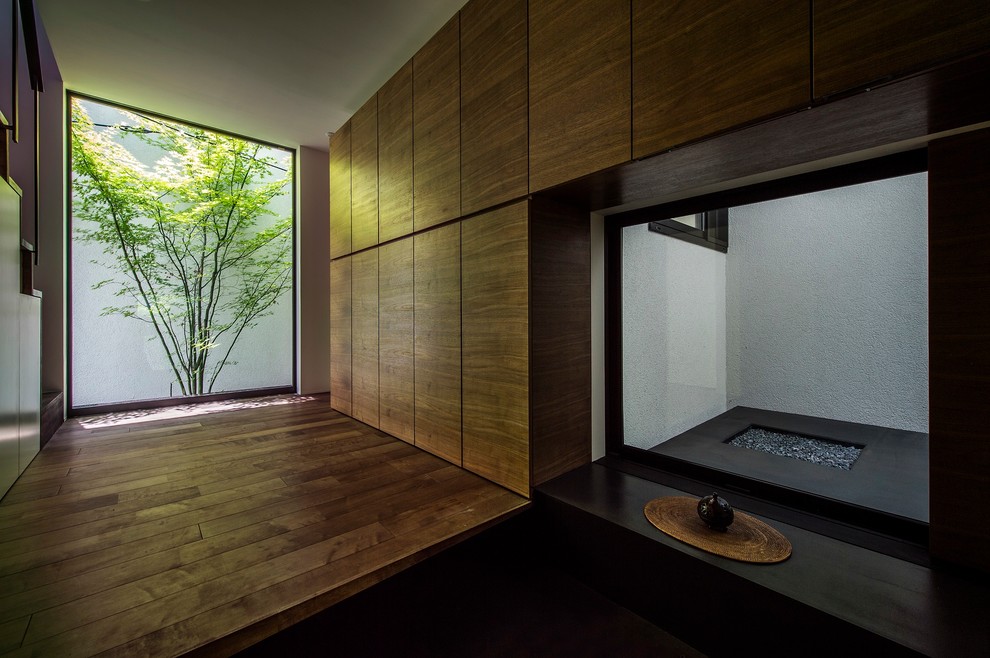 Contemporary entry hall in Kyoto with brown walls, dark hardwood floors and brown floor.