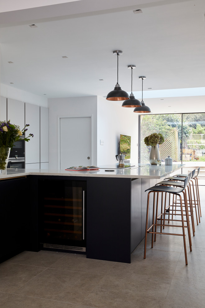 This is an example of a large modern l-shaped open plan kitchen in London with a single-bowl sink, flat-panel cabinets, white cabinets, marble worktops, white appliances, a breakfast bar, white worktops and a coffered ceiling.