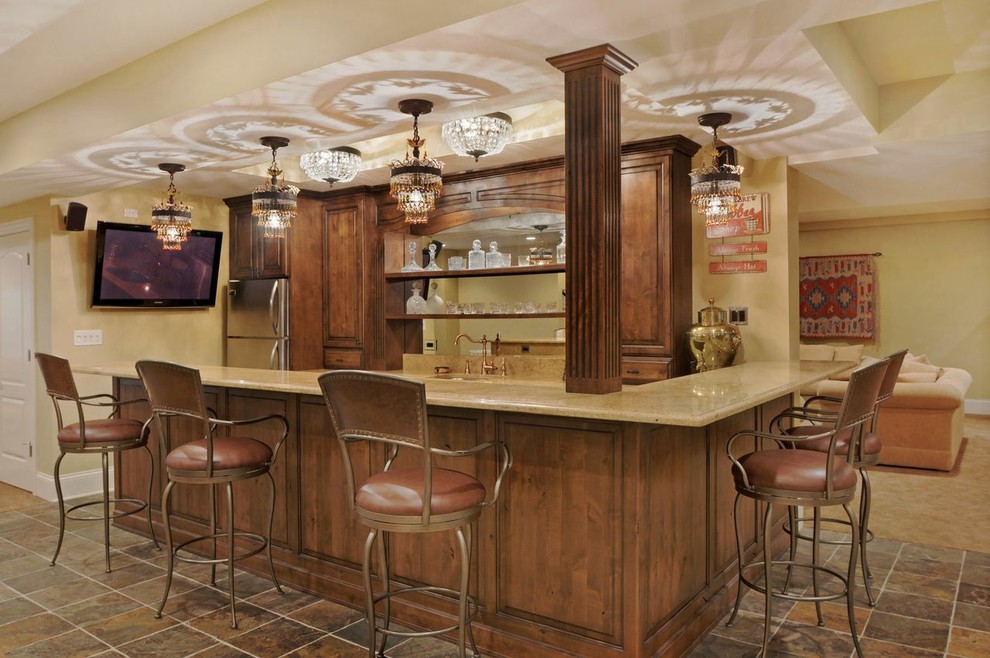 Inspiration for a large traditional u-shaped seated home bar in Chicago with an undermount sink, raised-panel cabinets, quartz benchtops, mirror splashback, slate floors, brown floor, dark wood cabinets and beige benchtop.