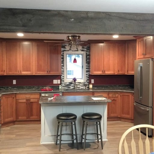 Large transitional u-shaped kitchen photo with recessed-panel cabinets, medium tone wood cabinets, granite countertops, multicolored backsplash, stainless steel appliances, an island and multicolored countertops