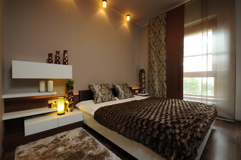 Photo of a contemporary bedroom with beige walls and dark hardwood floors.