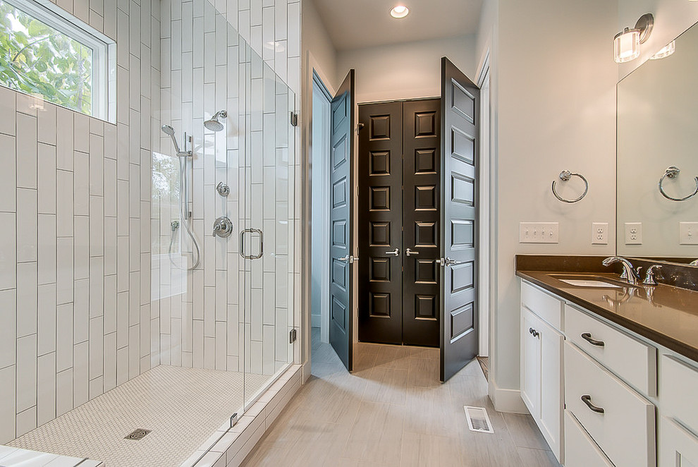 Design ideas for a mid-sized transitional master bathroom in Nashville with recessed-panel cabinets, white cabinets, a shower/bathtub combo, white tile, ceramic tile, white walls, ceramic floors, an undermount sink, engineered quartz benchtops and a hinged shower door.