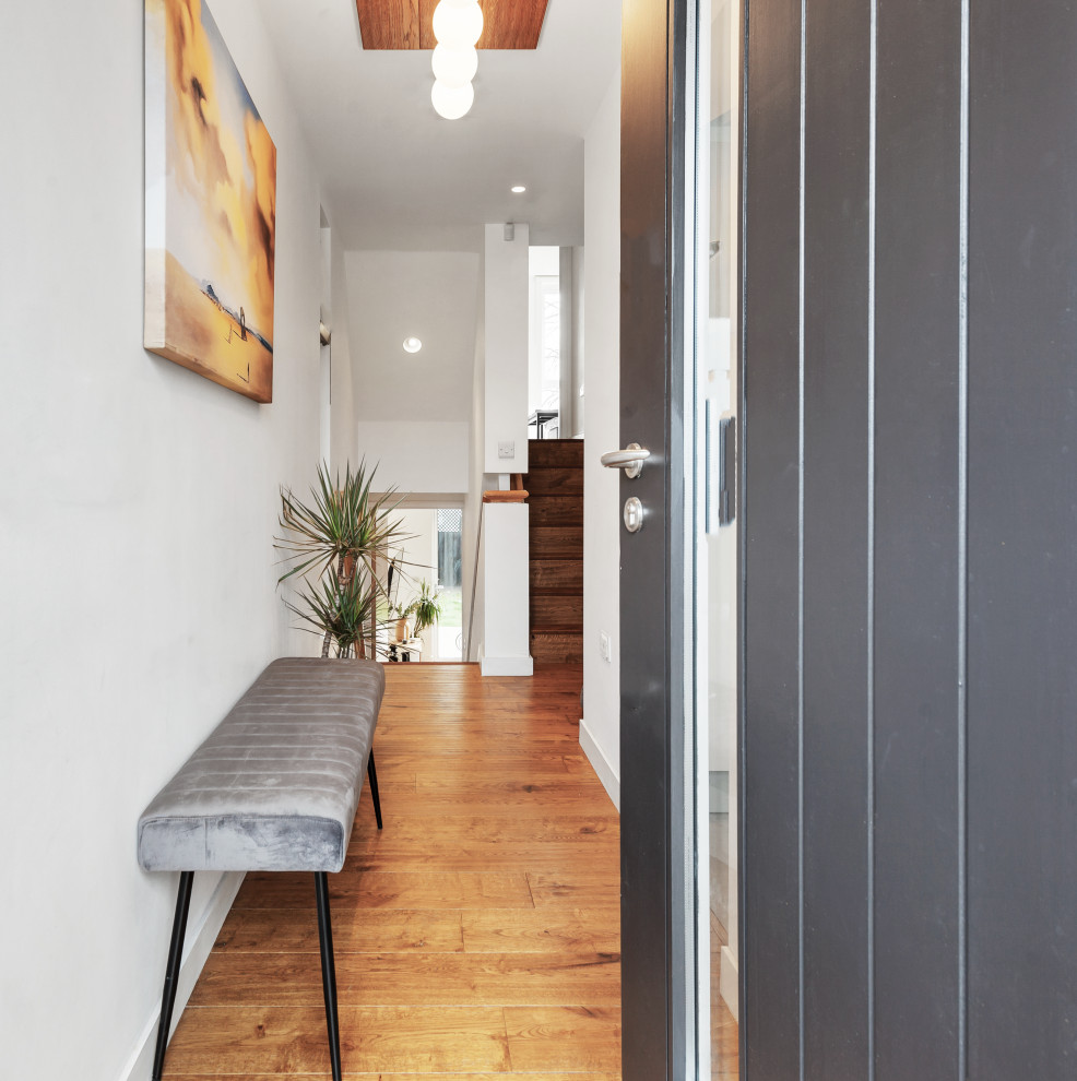 Kleiner Moderner Eingang mit Korridor, weißer Wandfarbe, Laminat, schwarzer Haustür, braunem Boden und Holzdecke in London