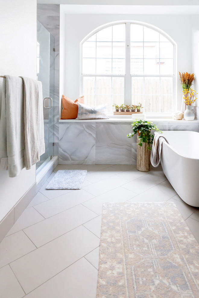 Design ideas for a transitional bathroom in Austin with a freestanding tub, an alcove shower, gray tile, white walls, white floor and a hinged shower door.