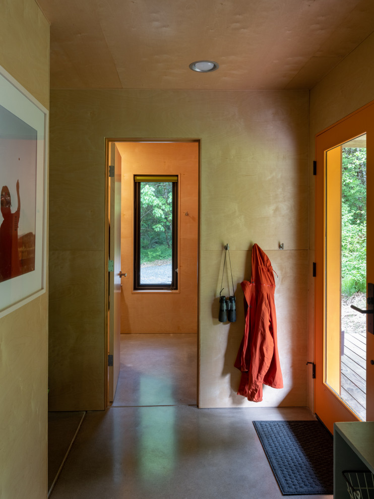 Inredning av en rustik liten hall, med betonggolv, en enkeldörr, en orange dörr och grått golv