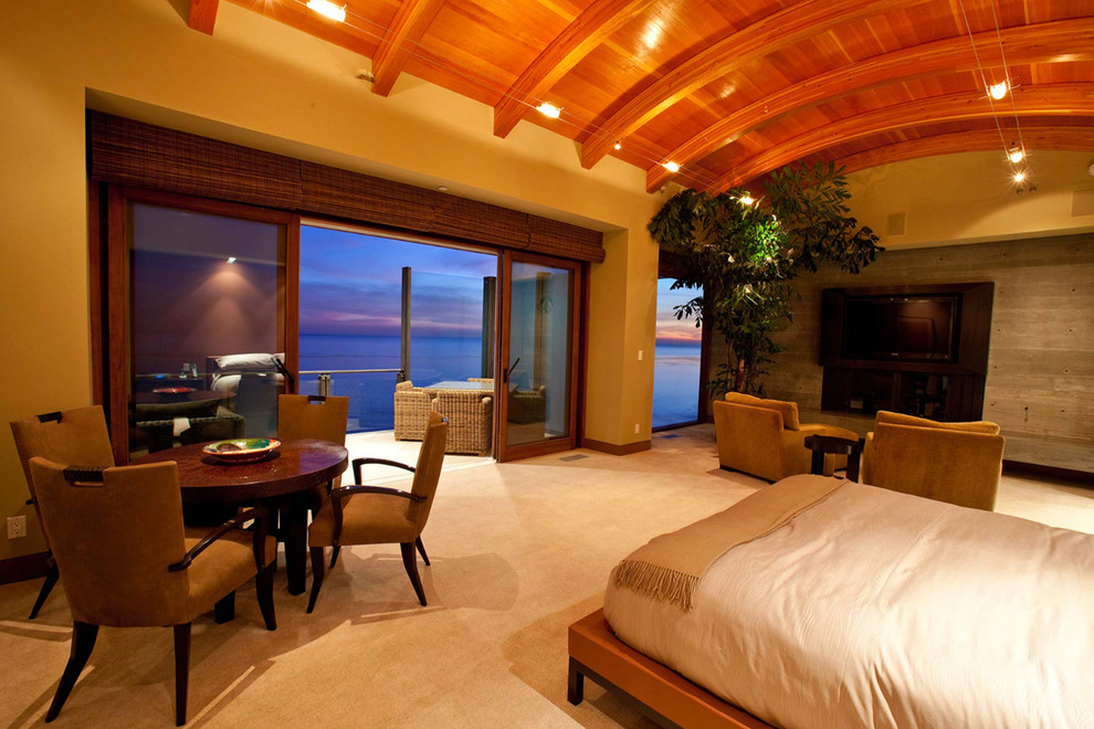 Expansive beach style loft-style bedroom in Los Angeles with beige walls, ceramic floors, a standard fireplace and a concrete fireplace surround.