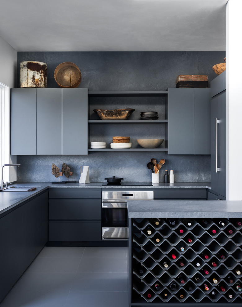 Inspiration for a modern u-shaped kitchen in New York with flat-panel cabinets, grey cabinets, concrete benchtops, grey splashback, stainless steel appliances, grey floor and grey benchtop.