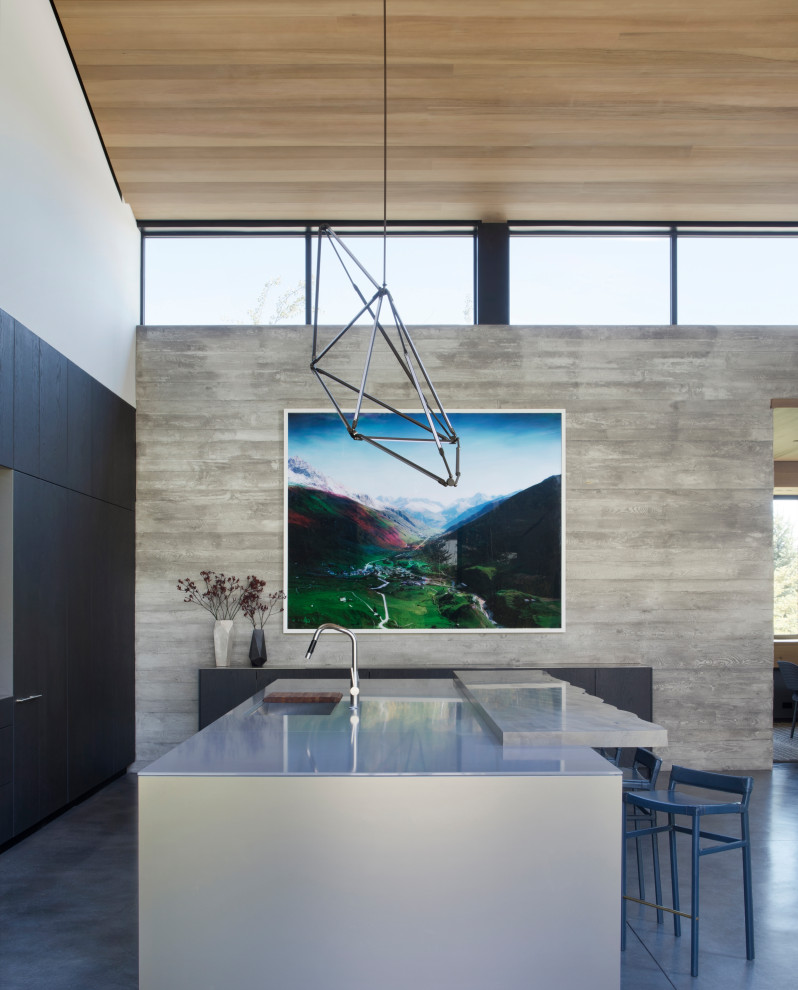 Open concept kitchen - large rustic single-wall concrete floor, gray floor and vaulted ceiling open concept kitchen idea with a drop-in sink, flat-panel cabinets, dark wood cabinets, granite countertops, stainless steel appliances, an island and beige countertops
