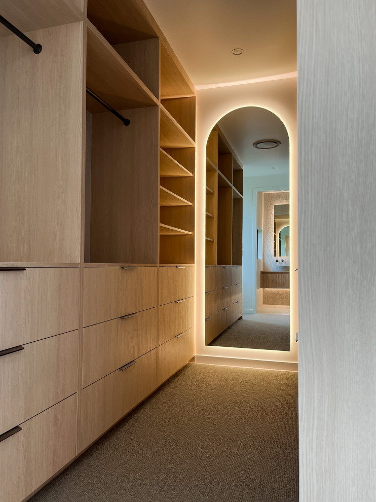 Стильный дизайн: большая гардеробная комната унисекс в современном стиле с светлыми деревянными фасадами, ковровым покрытием и серым полом - последний тренд