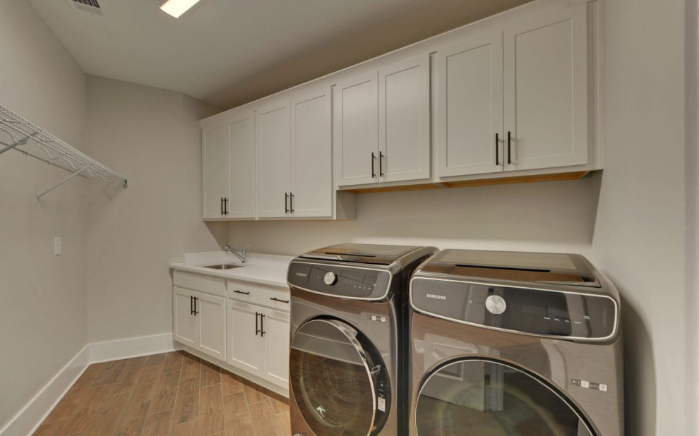This is an example of a country utility room in Atlanta with a side by side washer and dryer.