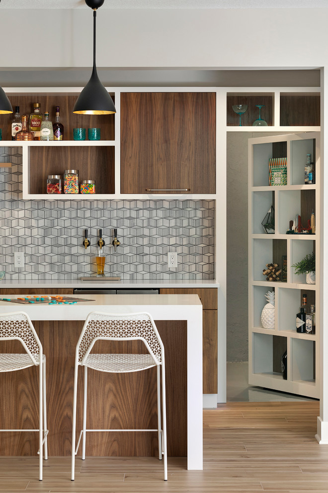 Inspiration for a mid-sized contemporary galley seated home bar in Minneapolis with an undermount sink, flat-panel cabinets, medium wood cabinets, quartz benchtops, grey splashback, marble splashback, porcelain floors, beige floor and white benchtop.