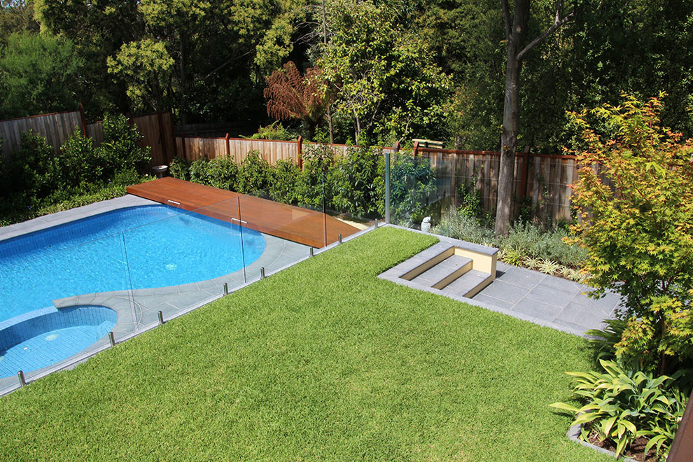 Large transitional backyard kidney-shaped lap pool in Melbourne with tile.