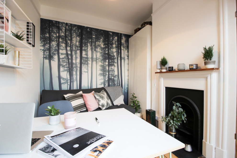 Cette photo montre une petite chambre d'amis scandinave avec un mur multicolore, un sol en bois brun, une cheminée standard, un manteau de cheminée en métal, un sol marron et du papier peint.