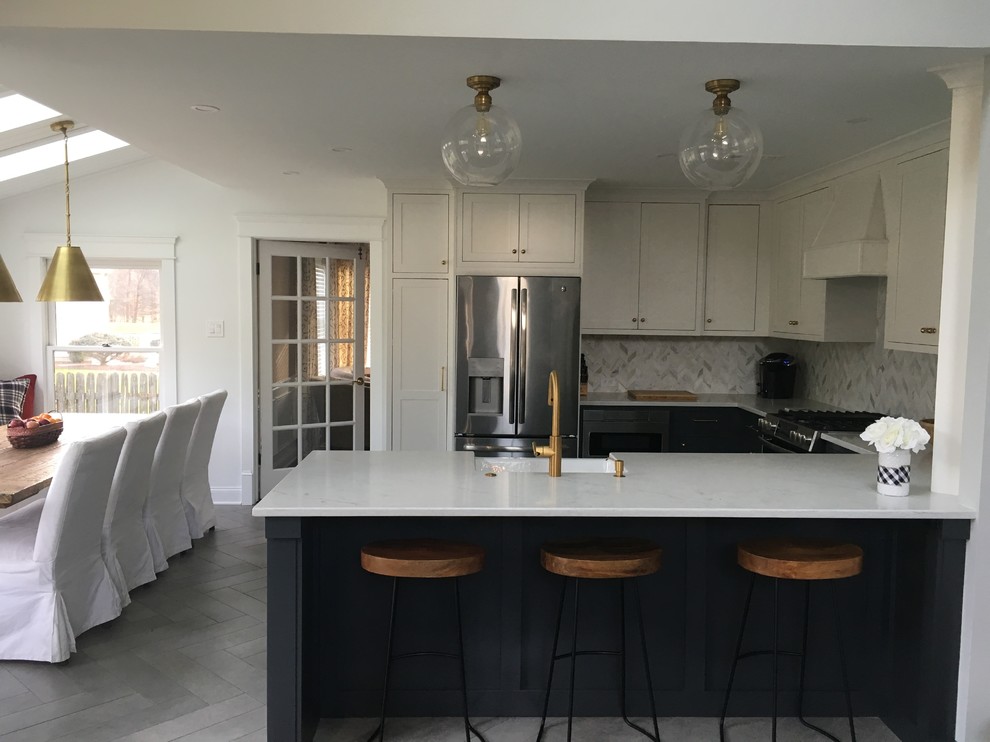 Design ideas for a mid-sized transitional u-shaped eat-in kitchen in Philadelphia with a farmhouse sink, beaded inset cabinets, blue cabinets, quartz benchtops, grey splashback, marble splashback, stainless steel appliances, ceramic floors, a peninsula, grey floor and white benchtop.