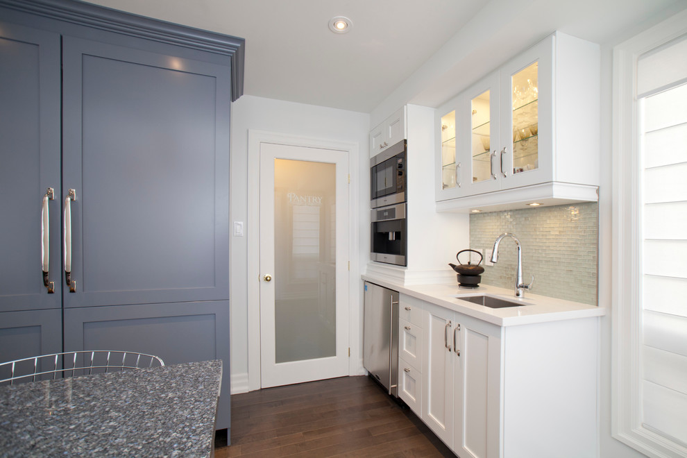 This is an example of a transitional kitchen in Toronto with a farmhouse sink, quartz benchtops, glass tile splashback, panelled appliances, medium hardwood floors and with island.