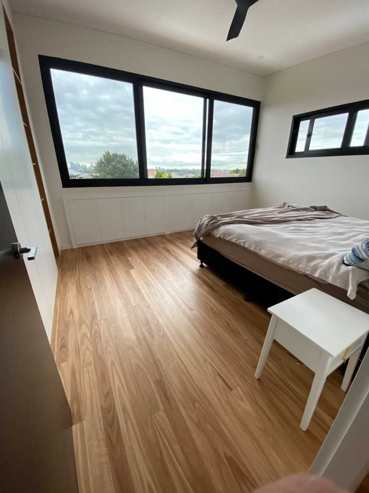 Inspiration for a medium sized contemporary guest bedroom in Sydney with white walls and light hardwood flooring.