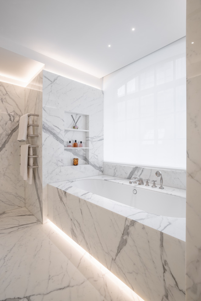 Bild på ett stort funkis vit vitt badrum med dusch, med släta luckor, vita skåp, ett platsbyggt badkar, en öppen dusch, en vägghängd toalettstol, vita väggar, marmorgolv, marmorbänkskiva, vitt golv och med dusch som är öppen
