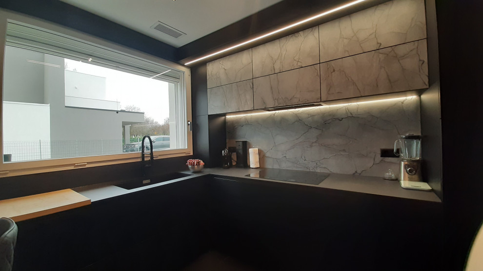 Photo of a mid-sized modern u-shaped separate kitchen in Other with a single-bowl sink, flat-panel cabinets, black cabinets, solid surface benchtops, grey splashback, black appliances, porcelain floors, a peninsula, black floor and grey benchtop.