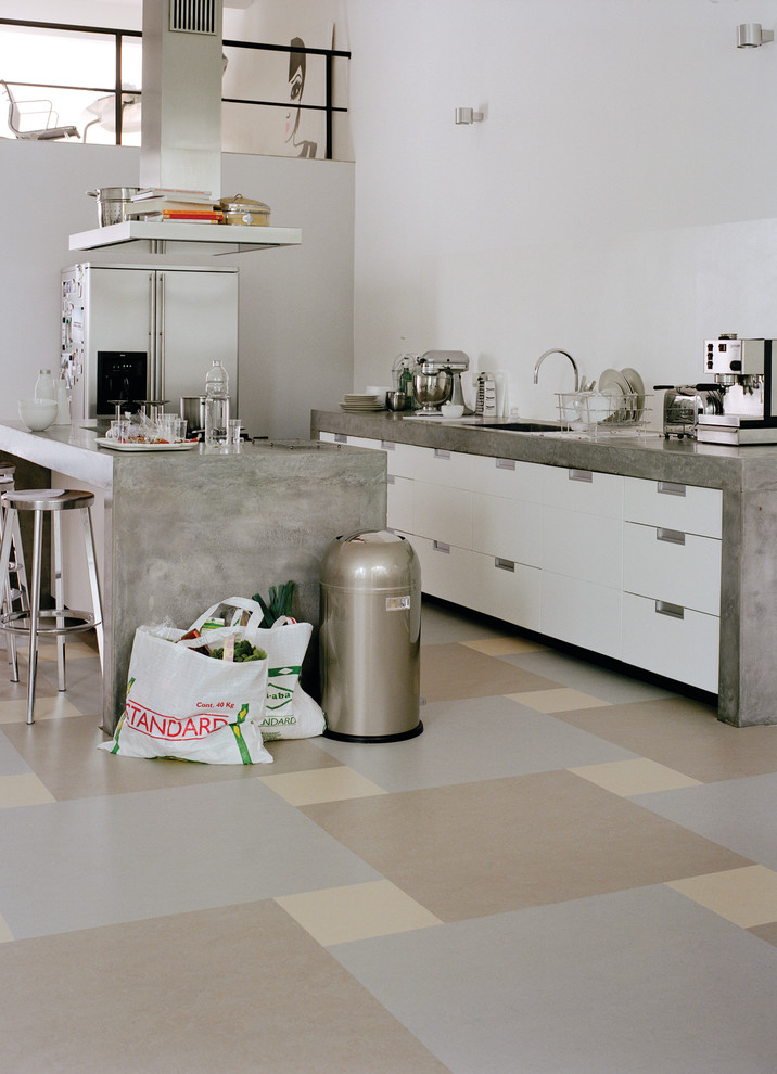 Design ideas for a mid-sized industrial galley separate kitchen in Chicago with linoleum floors, a drop-in sink, flat-panel cabinets, white cabinets, stainless steel appliances and with island.