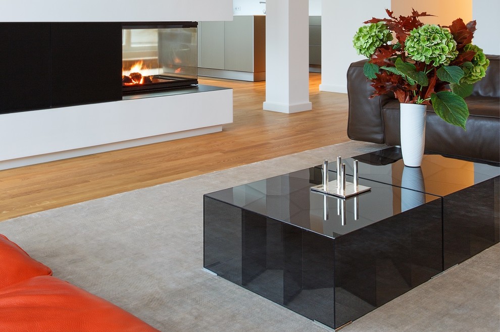 Große, Fernseherlose, Offene Moderne Bibliothek mit weißer Wandfarbe, braunem Holzboden, Kaminofen, Kaminumrandung aus Beton und beigem Boden in Berlin