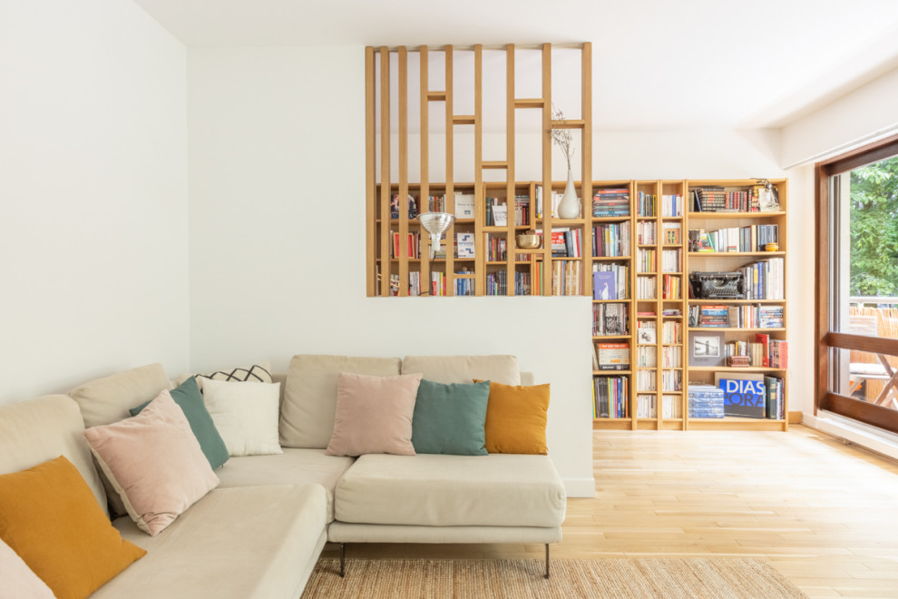 This is an example of a large contemporary open concept living room in Paris with a library, white walls and light hardwood floors.
