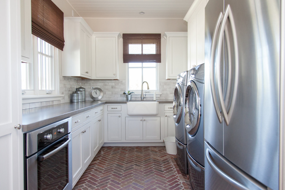 Inspiration for a large transitional u-shaped utility room in Phoenix with a farmhouse sink, white cabinets, beige walls, brick floors, a side-by-side washer and dryer and shaker cabinets.