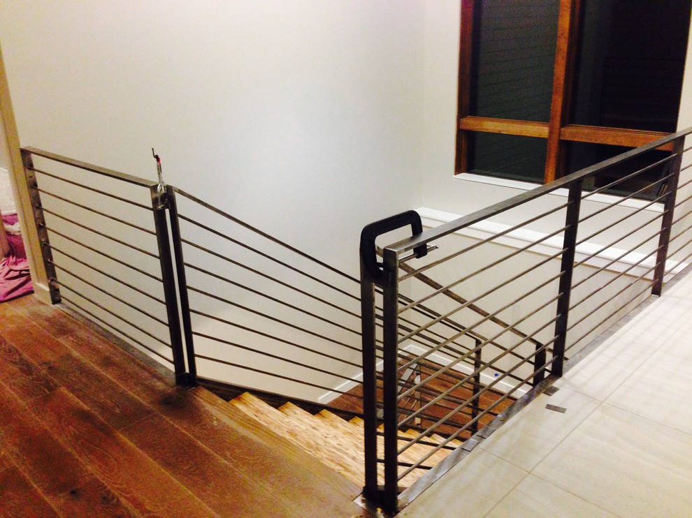 This is an example of a large modern wood u-shaped staircase in Denver with wood risers and metal railing.