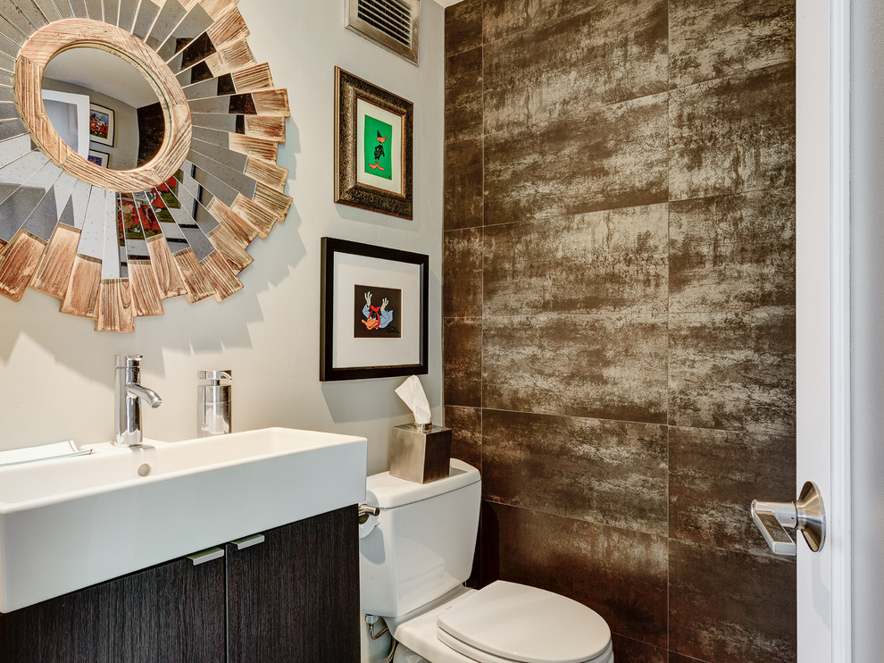 Photo of a mid-sized contemporary powder room in Columbus with a trough sink, flat-panel cabinets, dark wood cabinets, a two-piece toilet, brown tile, white walls and stone tile.