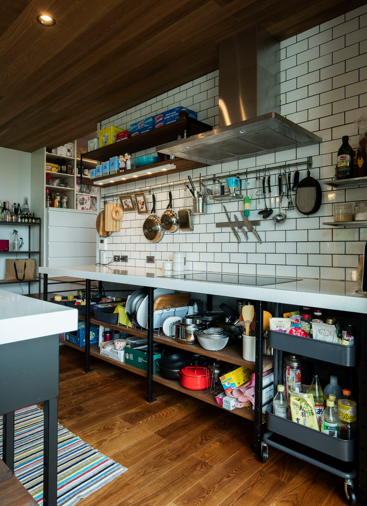 Large industrial galley open plan kitchen in Other with an integrated sink, open cabinets, black cabinets, granite benchtops, white splashback, subway tile splashback, black appliances, dark hardwood floors, with island, brown floor and white benchtop.