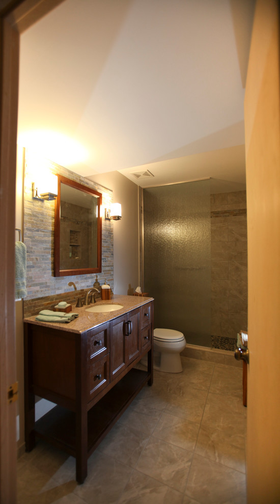 Photo of a mid-sized transitional bathroom in Minneapolis with an undermount sink, recessed-panel cabinets, dark wood cabinets, granite benchtops, an open shower, a two-piece toilet, multi-coloured tile, stone tile, brown walls and porcelain floors.